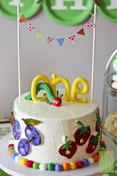 a birthday cake with the word one on top and decorations around it, sitting on a table