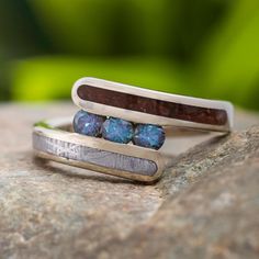 two silver rings with blue and brown stones on top of each other sitting on a rock