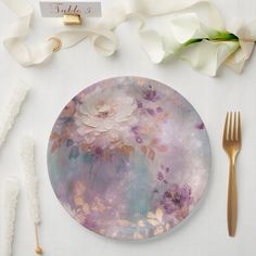 a plate with flowers on it sitting next to some forks and napkins, along with other items