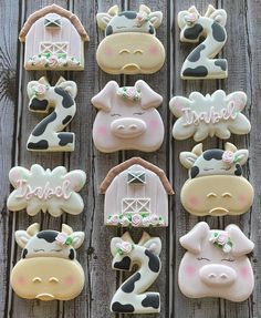 decorated cookies in the shape of farm animals are arranged on a wooden table with barn doors