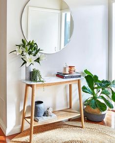 a mirror sitting on top of a wooden table next to a plant and potted plants