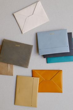 several different colored envelopes sitting next to each other on top of a white table