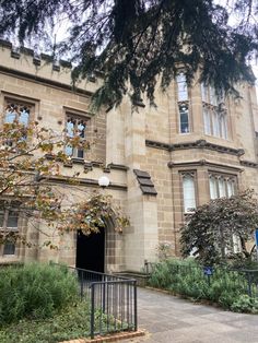 an old building with trees and bushes in front