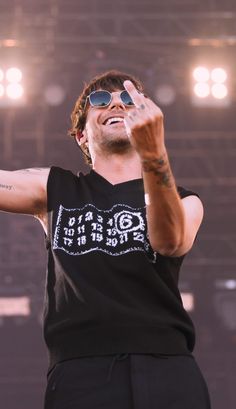 a man with sunglasses on his head and arms raised in the air as he sings