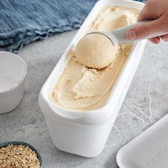 a person scooping ice cream into a container