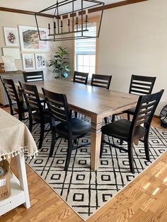 a dining room table with black chairs and a rug on the floor in front of it