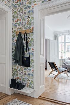 a coat rack with two coats hanging on it in front of a floral wallpaper