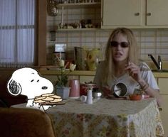 a woman sitting at a table in front of a cartoon dog with sunglasses on her head