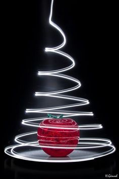 a red apple sitting on top of a table next to a christmas tree with white lights