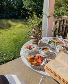 an open book is sitting on a table with food and coffee outside in the sun