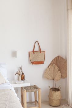 a room with a bed, table and basket hanging on the wall next to it