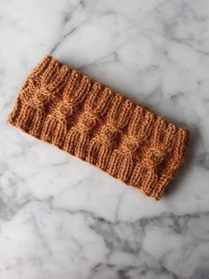 an orange knitted headband sitting on top of a marble counter