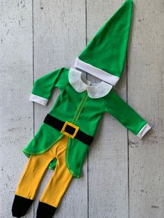 a green and yellow elf costume laying on top of a wooden floor