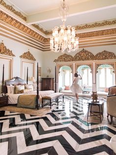 a woman standing in a large bedroom with black and white flooring