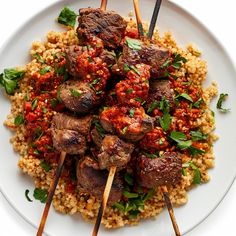 a white plate topped with meat and rice covered in sauce next to chopsticks