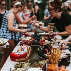 a group of people standing around a table filled with food