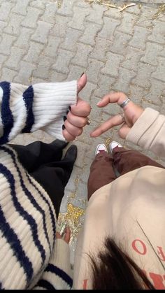 two people sitting on the ground with their hands in each other's pockets and fingers pointing at them