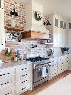 a kitchen with white cabinets and brick wall