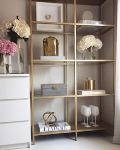 a shelf filled with vases and flowers next to a dresser