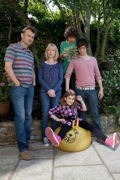 a group of people that are standing in front of a ball on the ground with trees behind them