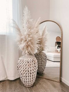 a mirror sitting on top of a wooden floor next to a basket filled with feathers