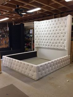 a white bed frame sitting inside of a room next to a wall with lights on it