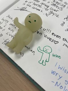 a small plastic figure sitting on top of a piece of paper next to a handwritten note