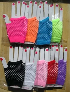 several pairs of colorful gloves are on display in plastic bags and lined up against a wooden table