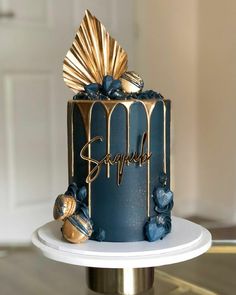 a blue and gold birthday cake with the word happily written on it's side