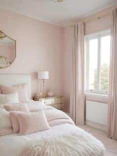 a bedroom with pink walls and white fur on the bed, along with a large window