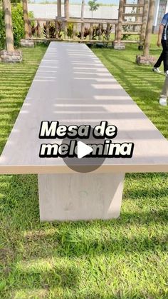 a long table in the middle of a grassy area with people walking around it and an advertisement for mesde melrima