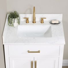 a bathroom sink with gold faucets and a white cabinet in front of it