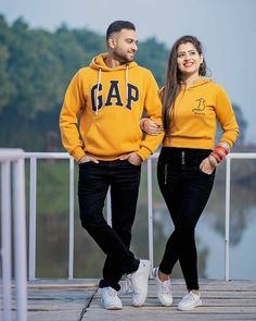 a man and woman in yellow hoodies standing on a dock next to each other