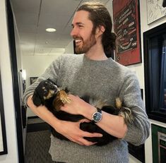 a man is holding two small dogs in his arms and smiling at the camera while standing in an office