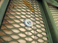 an old green metal door with a button on it's side and wood floor