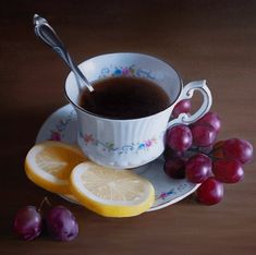 a painting of a cup of tea and some grapes on a plate with a spoon