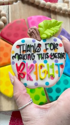 a hand holding a decorated cookie that says thanks for making this year bright