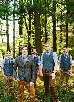 a group of men standing next to each other in front of trees with grass on the ground