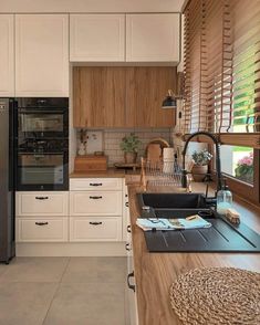 a kitchen with white cabinets and black appliances in it's center island next to a window