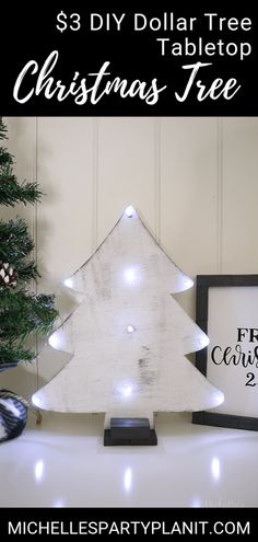 a white christmas tree sitting on top of a table next to a black and white sign