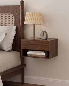 a night stand with a lamp on it next to a bed