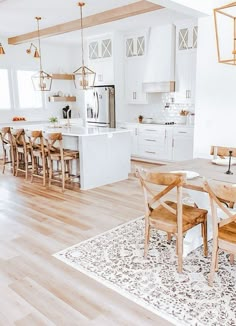 a kitchen and dining room with white cabinets, wood floors and an area rug on the floor