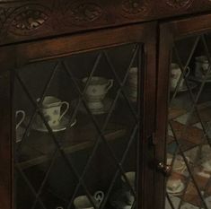 an old china cabinet with cups and saucers on it