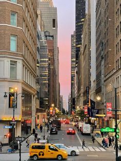 a busy city street filled with lots of traffic and tall buildings in the background at dusk