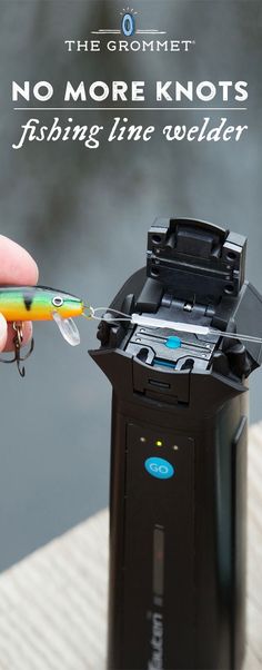 a person is holding a fishing lure in front of a small device that looks like a printer