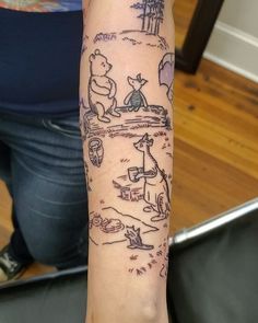 a person with a tattoo on their arm that has winnie the pooh drawings on it