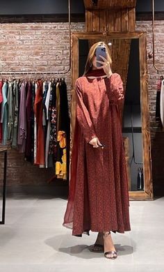 a woman taking a selfie in front of a mirror wearing a long red dress