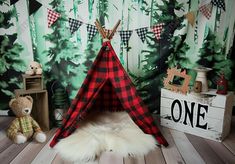 a red and black plaid teepee tent sitting on top of a wooden floor next to two teddy bears