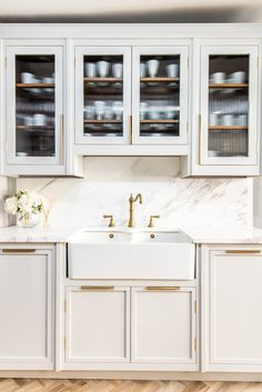 a kitchen with white cabinets and marble counter tops in the center, along with wooden flooring