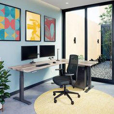 an office with two computer monitors and a desk in front of large windows that look out onto the backyard